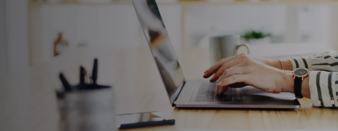 senhor sentado à secretária a consultar portátil