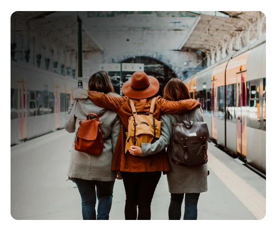 Grupo de 3 amigas abraçadas num terminal ferroviário