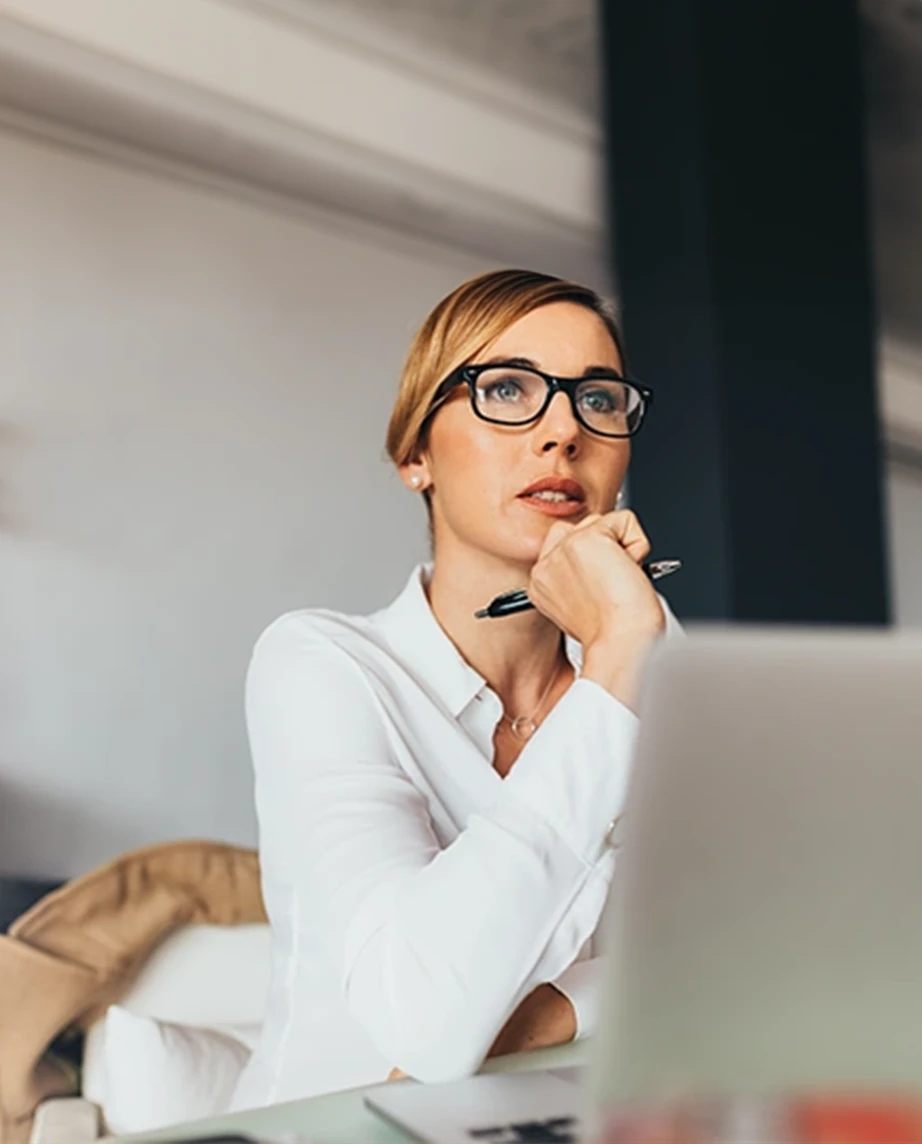 senhora em frente a computador, com caneta na mão