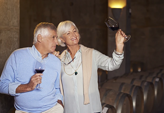 casal maduro numa cave de vinhos, com copos de vinho na mão