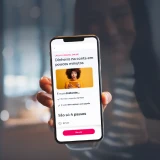 Senhora jovem a segurar o telemóvel com a App Millennium aberta no simulador do Crédito Pessoal Online