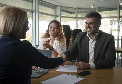 Casal em reunião de negócios a apertar a mão de uma consultora