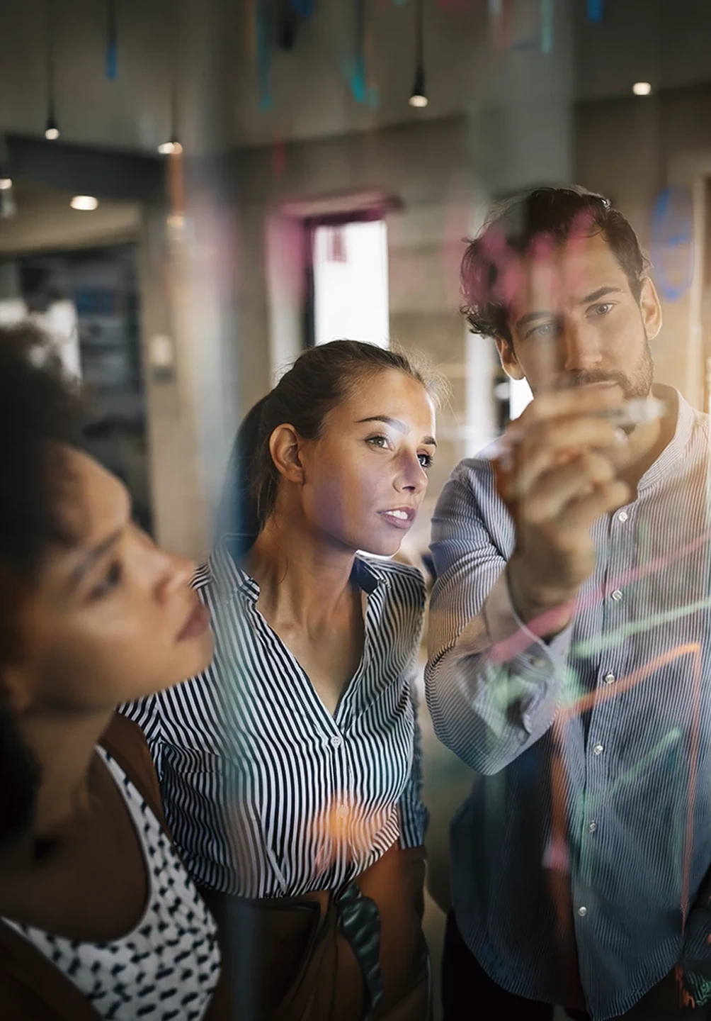 Team brainstorming ideas on a glass board in an office