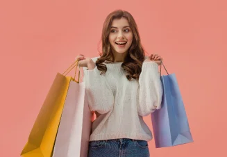 Rapariga com uma camisola de malha e calças de ganga a levantar 3 sacos de compras com as duas mãos