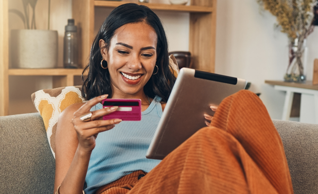 Mulher sorridente a fazer compras online num tablet com um cartão de crédito