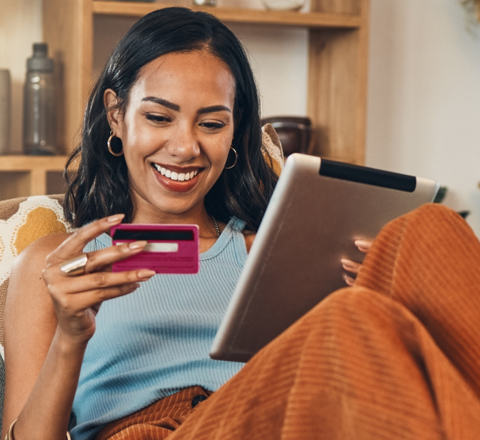 Mulher sorridente a fazer compras online num tablet com um cartão de crédito