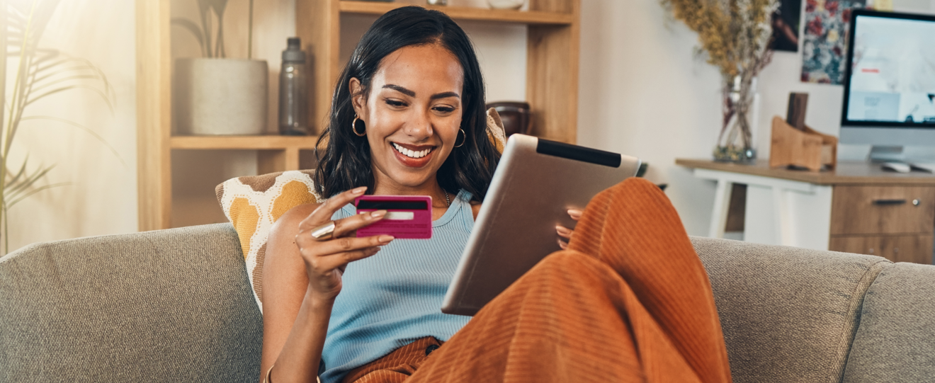 Mulher sorridente a fazer compras online num tablet com um cartão de crédito