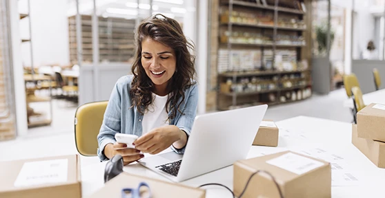senhora sorridente numa secretária num armazém, com TPA na mão