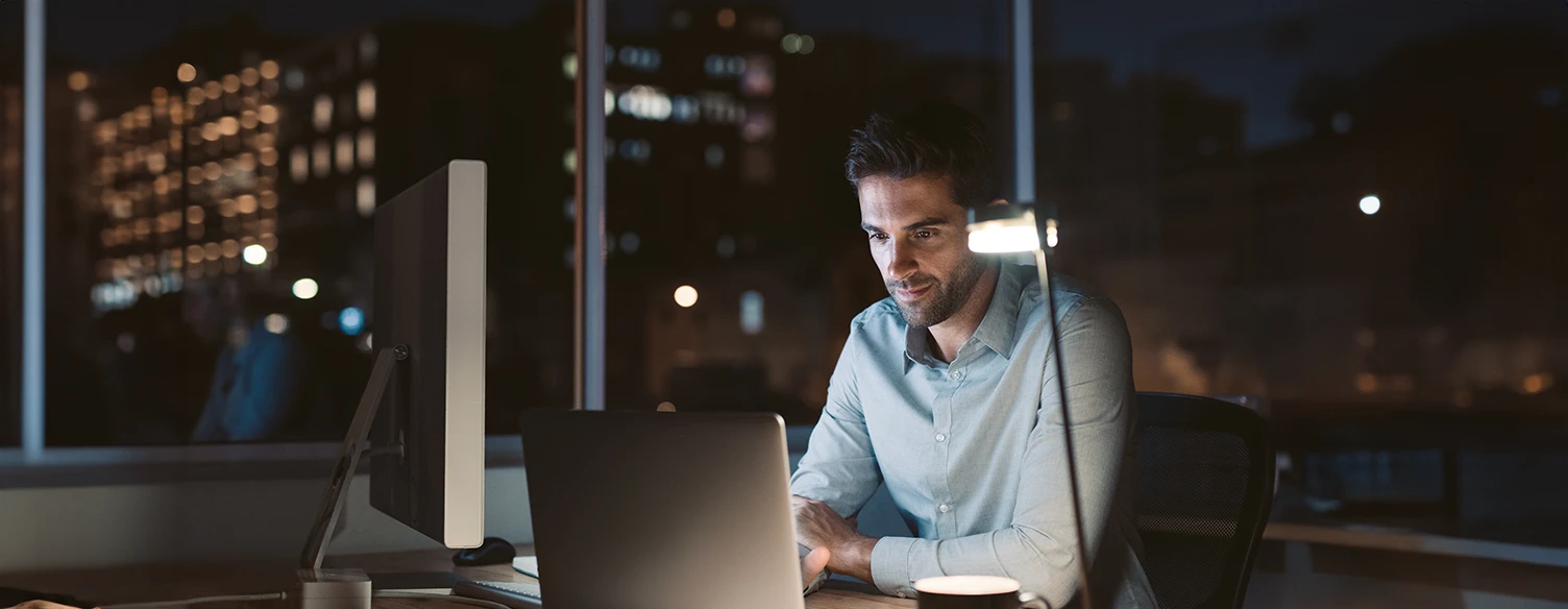 man sitting at the desk, with a laptop and a coffee cup