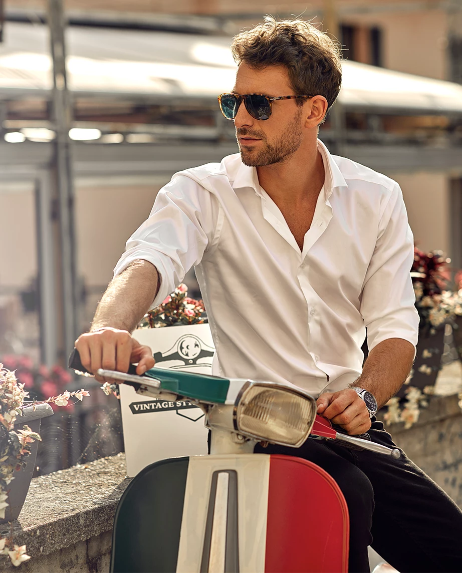 man in a scooter, next to a wall with flowers