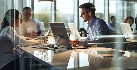 3 pessoas numa secretária, num escritório, a conversar