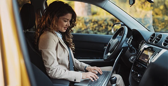 senhora sentada no carro, com computador ao colo