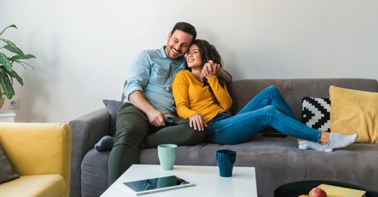 Casal sorridente relaxa no sofá da sala de estar