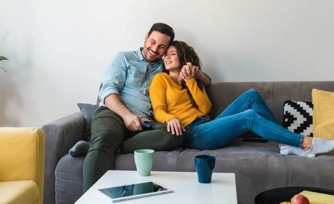 Casal sorridente relaxa no sofá da sala de estar