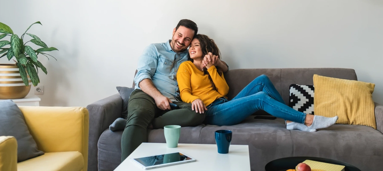 Casal sorridente relaxa no sofá da sala de estar
