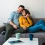 Casal sorridente relaxa no sofá da sala de estar