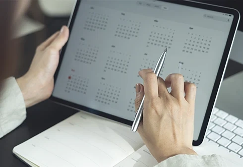 Pessoa a consultar um calendário digital num tablet com uma caneta