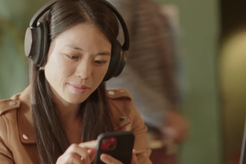 Rapariga de headphones a olhar para o seu telemóvel