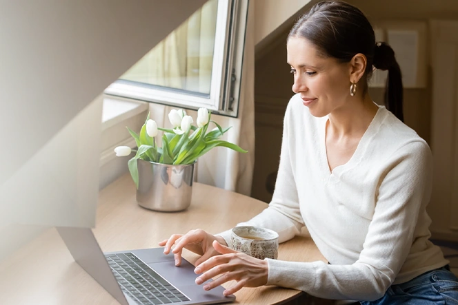 woman sitting at a desk by the window, working on the computer