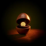 Guarda joias em formato de ovo de chocolate, meio aberto com uma moeda de libra de ouro no interior