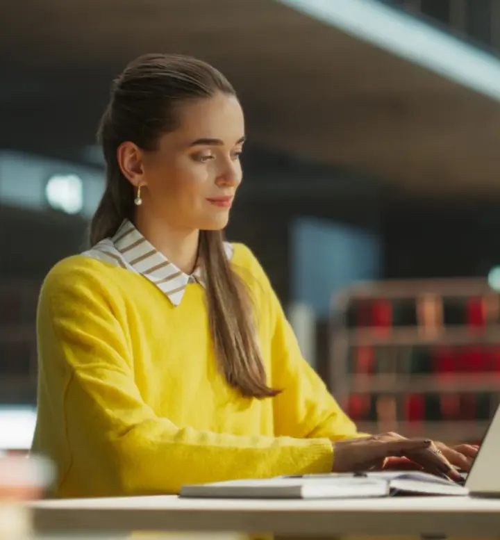 Jovem numa biblioteca a utilizar o seu computador