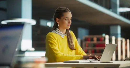 Jovem numa biblioteca a utilizar o seu computador