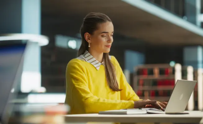 Jovem numa biblioteca a utilizar o seu computador