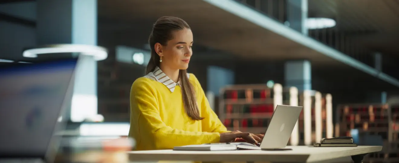 Jovem numa biblioteca a utilizar o seu computador