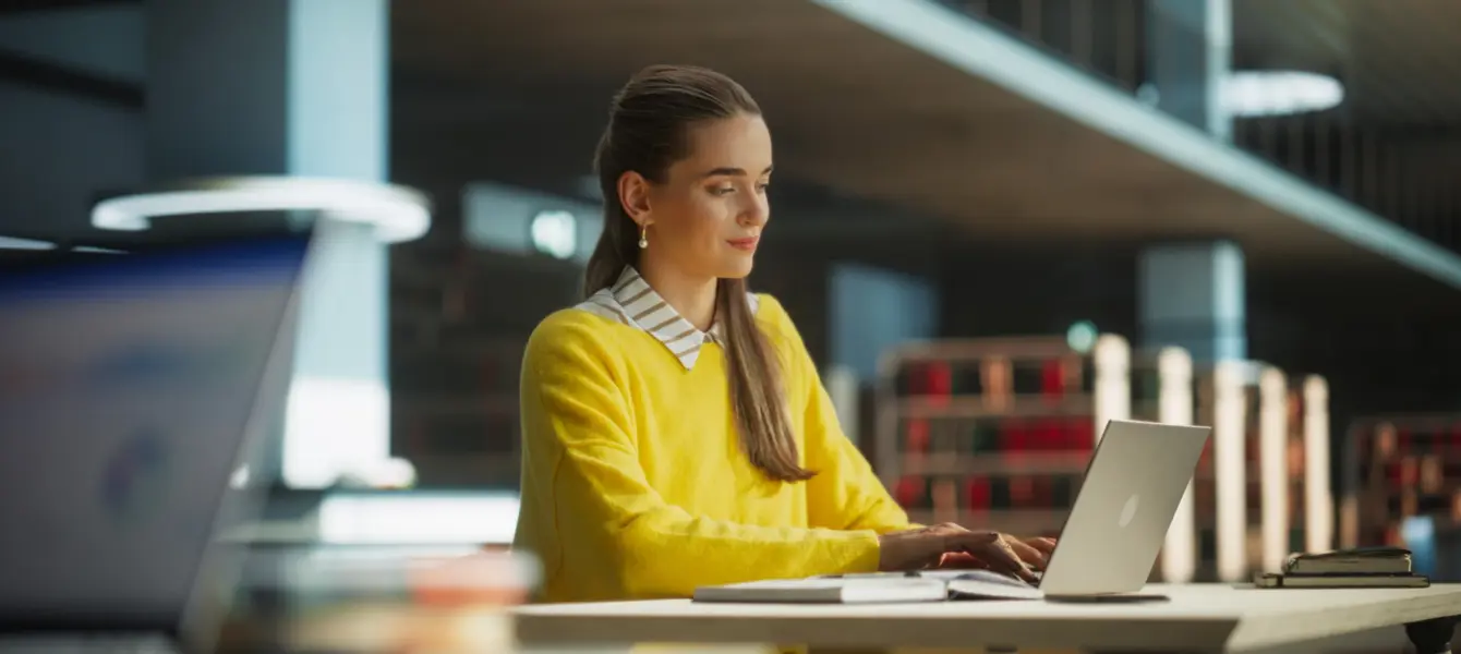 Jovem numa biblioteca a utilizar o seu computador
