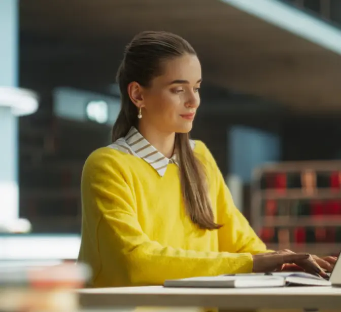 Jovem numa biblioteca a utilizar o seu computador
