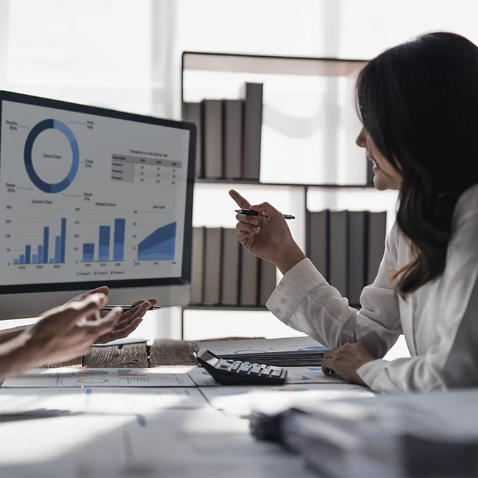 gestora sentada a uma secretária, a mostrar gráficos e a falar com cliente