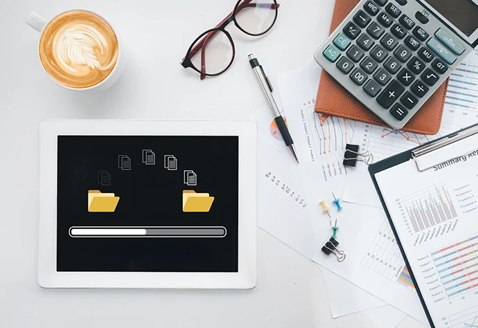 vista superior de secretária com tablet, calculadora, caneta, óculos, papés e chávena de café