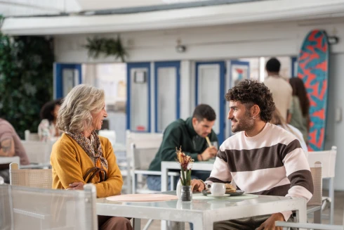 Custódia Gallego, a representar a personagem Fernanda Guimarães, e o José Condessa a conversarem num bar de praia