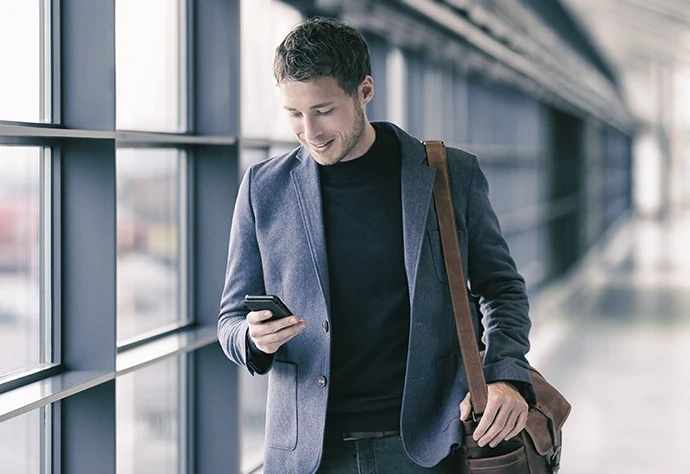 Homem a caminhar num corredor moderno enquanto utiliza o telemóvel