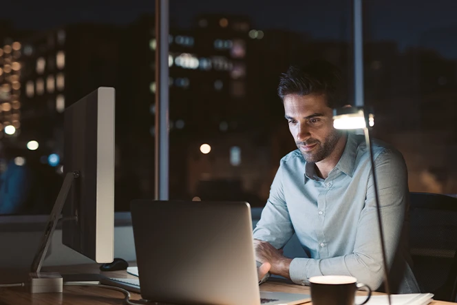 man sitting at the desk, with a laptop and a coffee cup