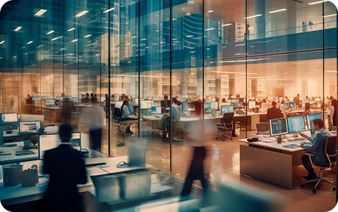 escritório grande, com paredes de vidro, várias secretárias com pessoas a trabalhar