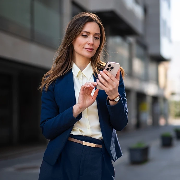 Mulher de fato a usar o telemóvel no exterior de um edifício