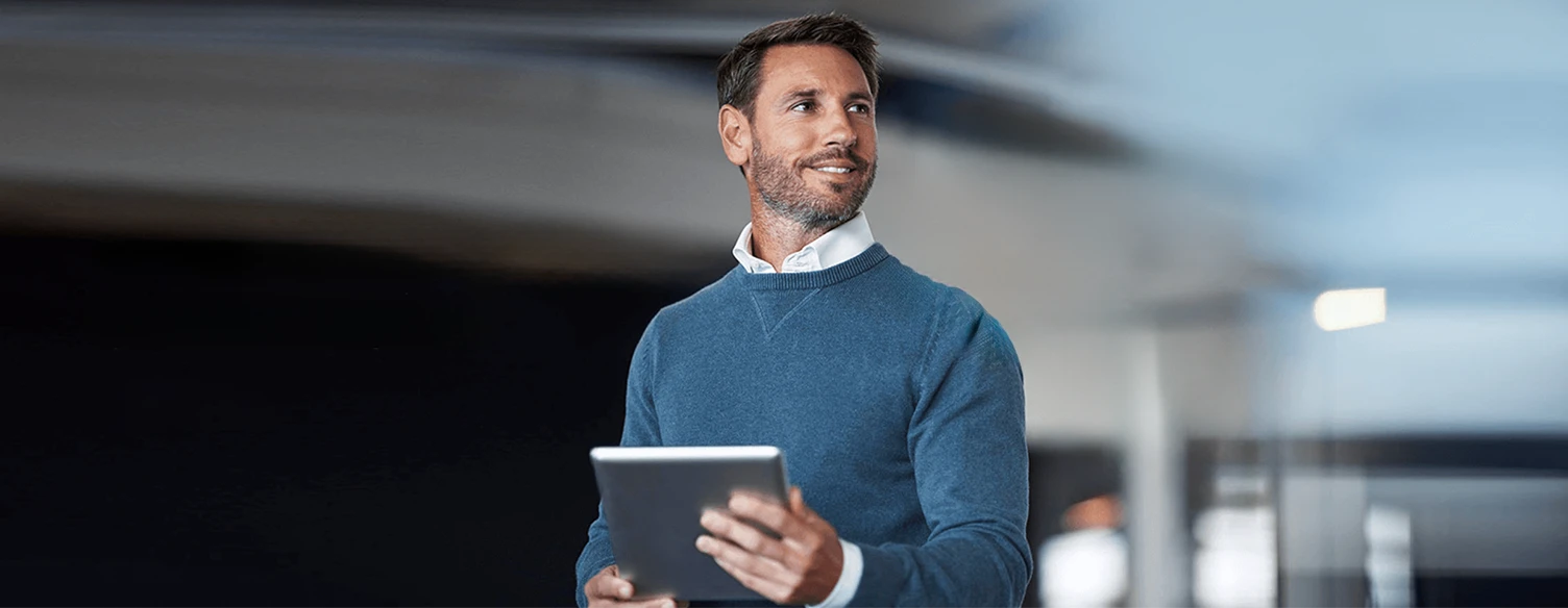 homem com camisola azul e tablet na mão