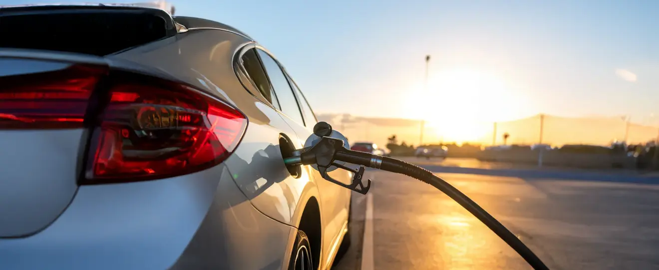Carro a ser abastecido numa bomba de gasolina ao pôr do sol