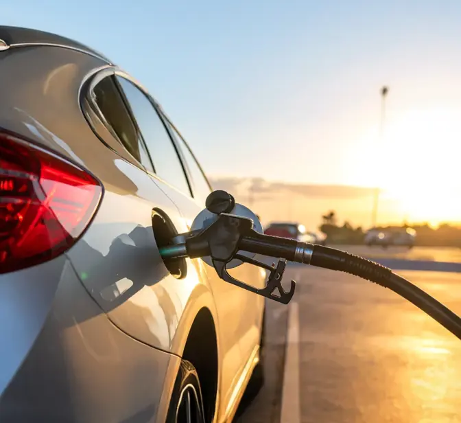 Carro a ser abastecido numa bomba de gasolina ao pôr do sol