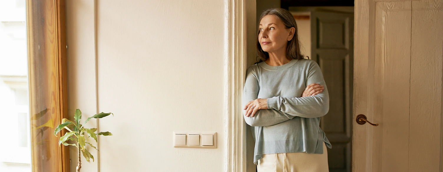 woman leaning against the door frame, looking out the window