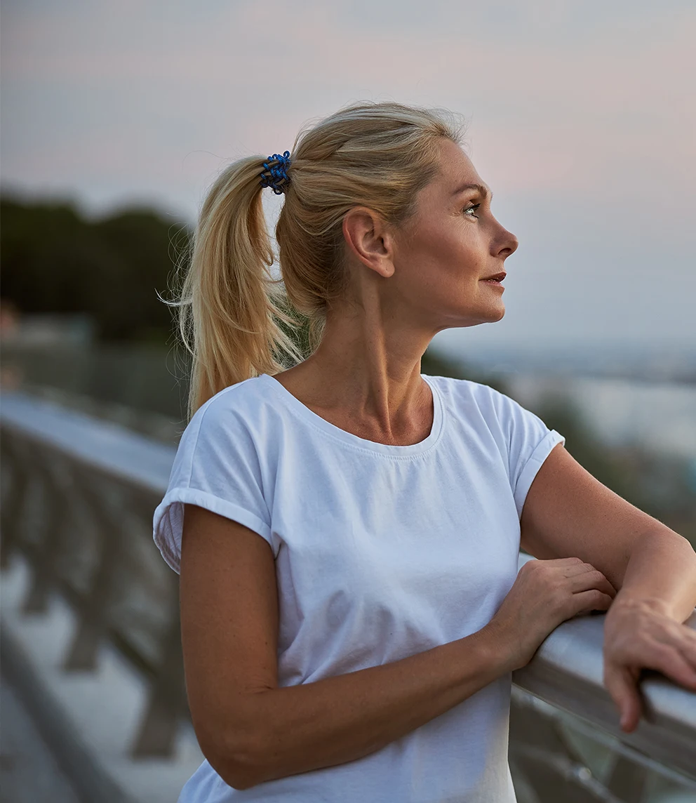 woman leaning on a balcony, looking at the horizon