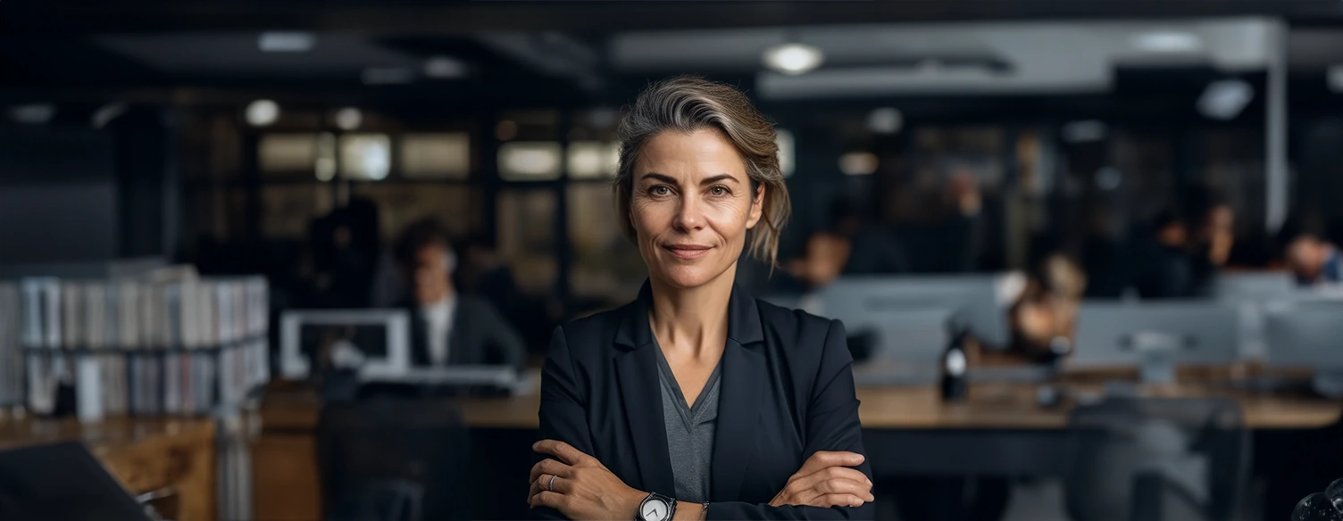 mulher, de blazer azul e braços cruzados, sorridente