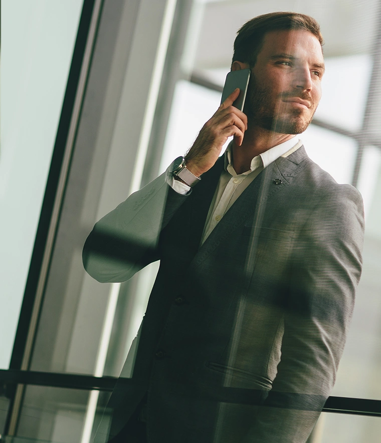 man in a suit and tie, talking on the phone, looking to the side